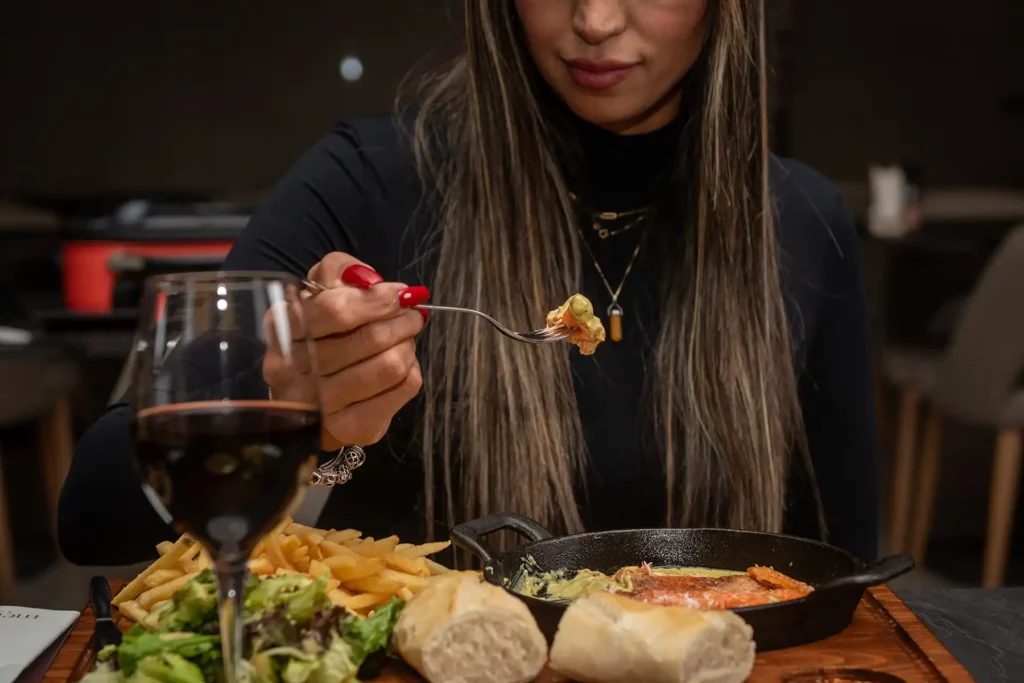 Guest enjoying dinner with wine, fries and signature sauce at Memories L’Entrecôte’s Restaurant Rooftop Larnaca