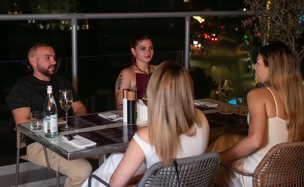 Four friends seated for an evening dinner at Memories L’Entrecôte’s Restaurant Rooftop in Larnaca