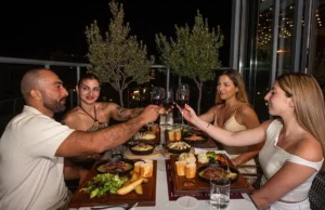 Friends toasting red wine during dinner at Memories L’Entrecôte’s Restaurant Rooftop in Larnaca