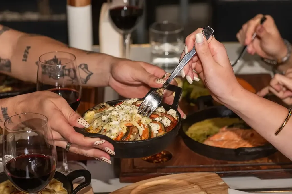 Guests sharing ratatouille with cheese at Memories L’Entrecôte’s Restaurant Rooftop in Larnaca