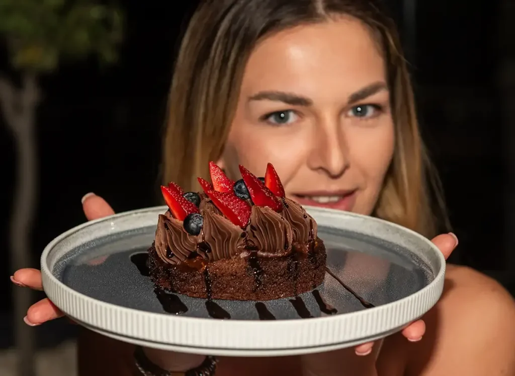 Woman presenting a chocolate dessert with berries at Memories L’Entrecôte’s Restaurant Rooftop in Larnaca